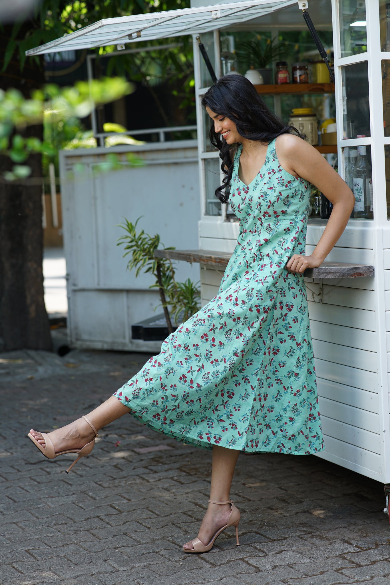 a woman in a green dress leaning against a truck.